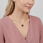 Gold black clover necklace worn with the head tilted down