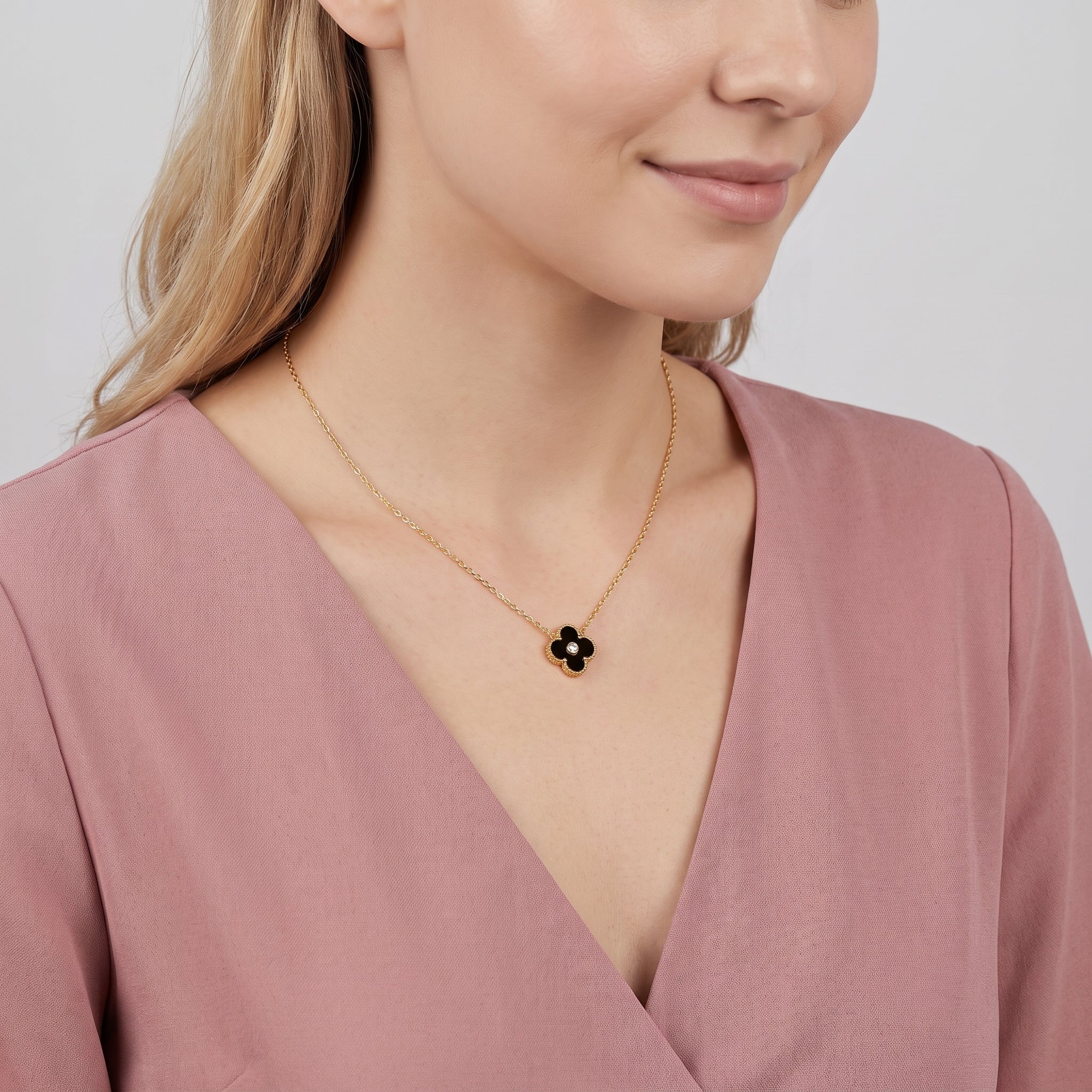 Gold black clover necklace worn with the head tilted down