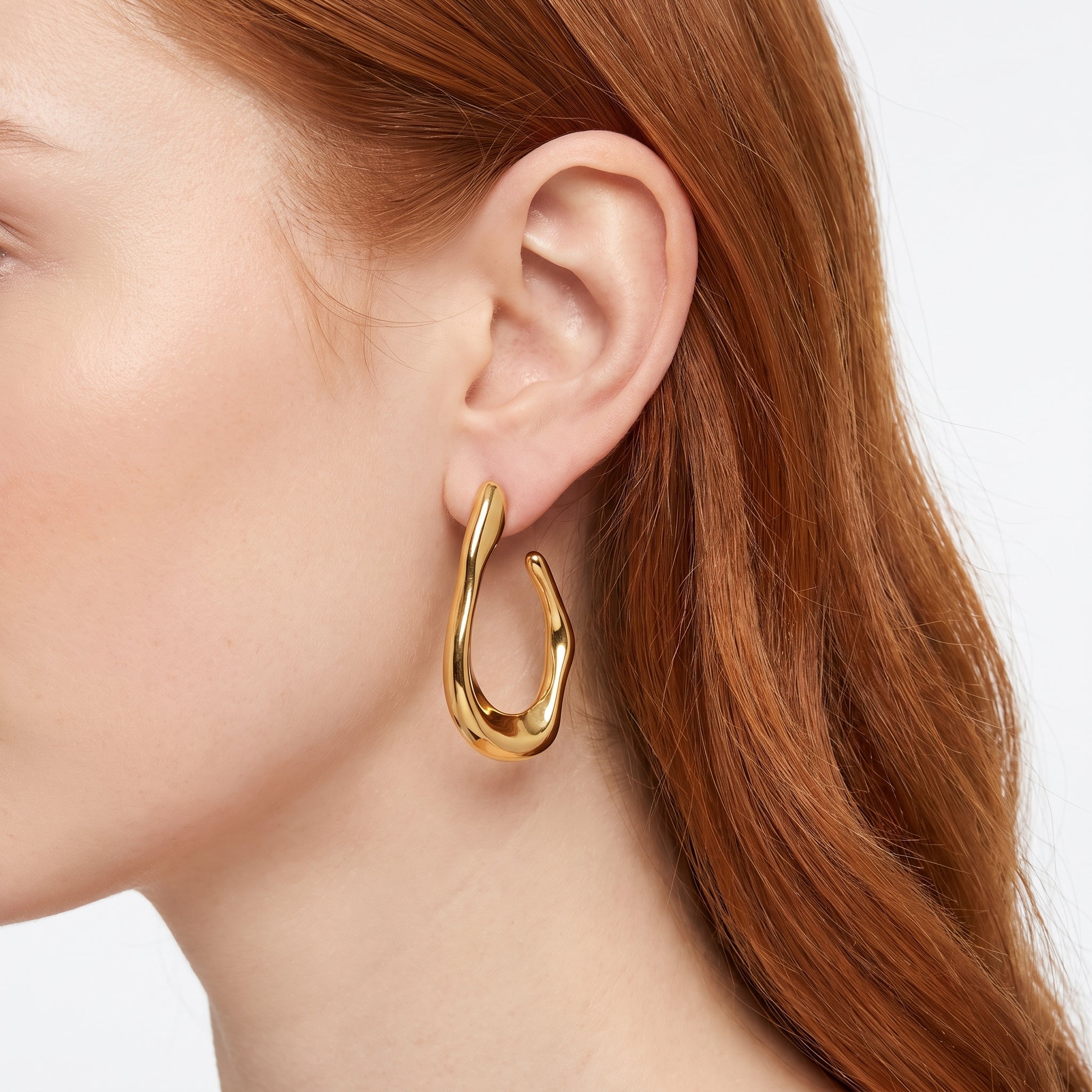 Gold chunky open hoop earring with molten shape, worn close-up