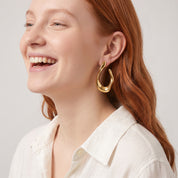Gold chunky open hoop earring worn with an ivory linen shirt