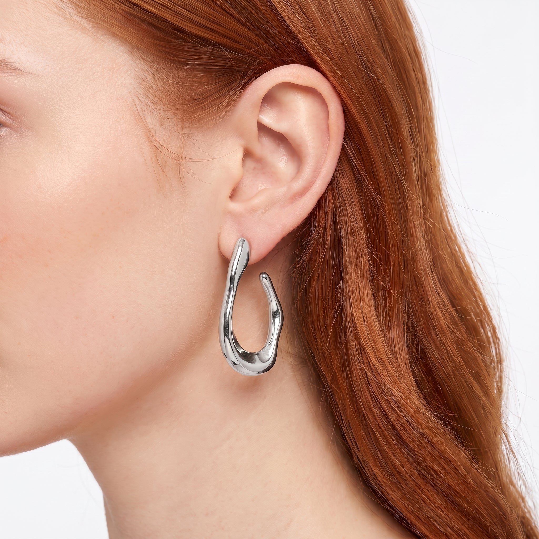Silver chunky open hoop earring with molten shape, worn close-up