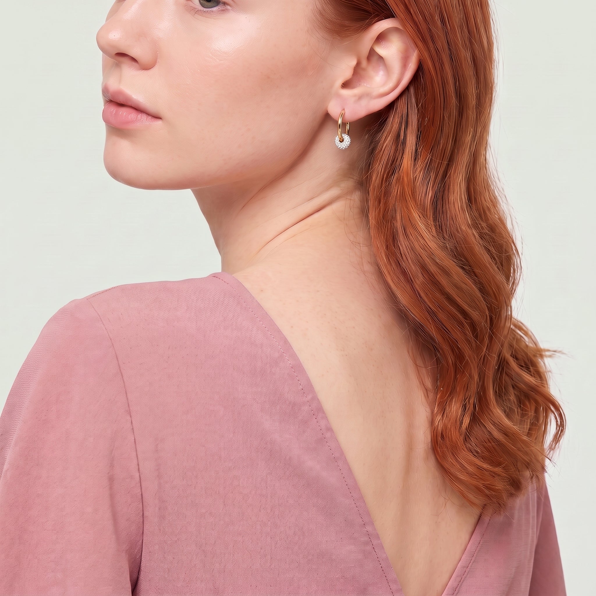 Gold crystal ball hoop seen over the shoulder, pink top