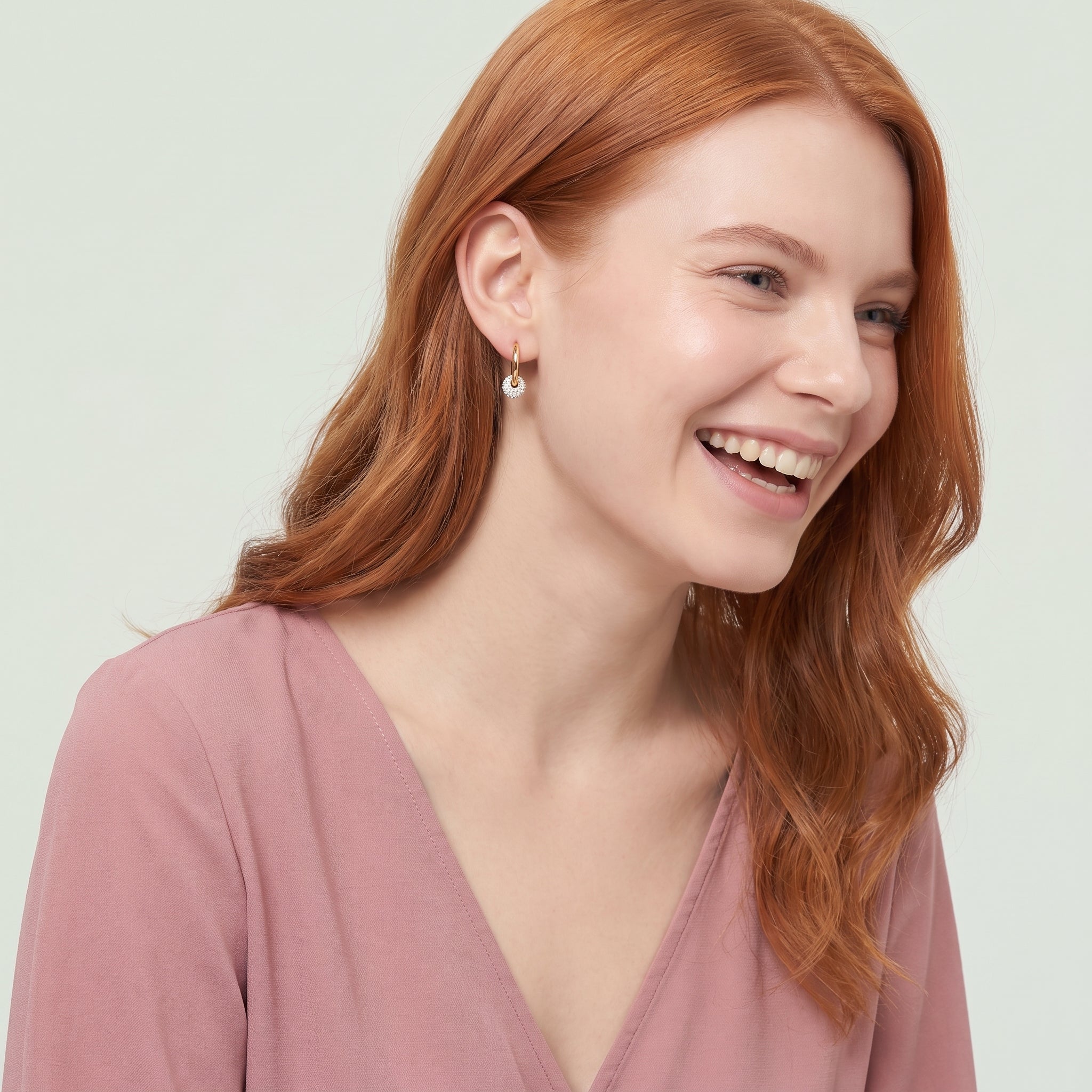 Gold crystal ball hoop earring in a laughing portrait