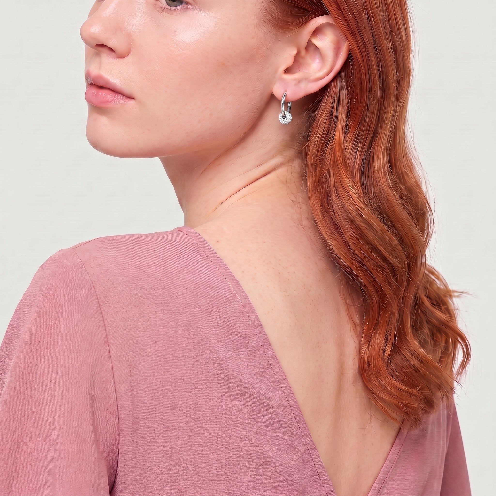Silver crystal ball hoop seen over the shoulder, pink top