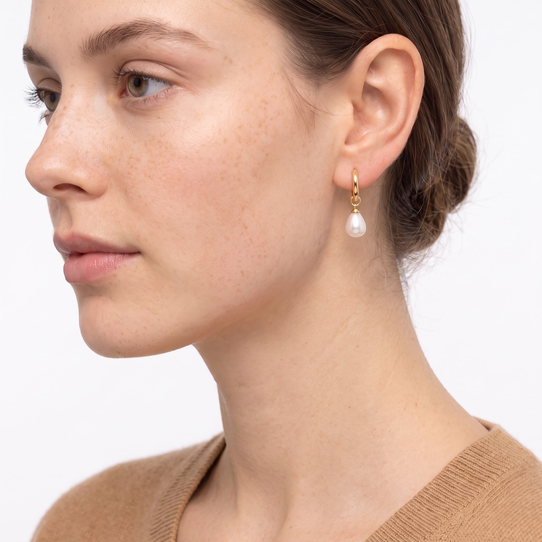 Side profile of woman wearing Odile gold huggie with teardrop pearl and camel sweater