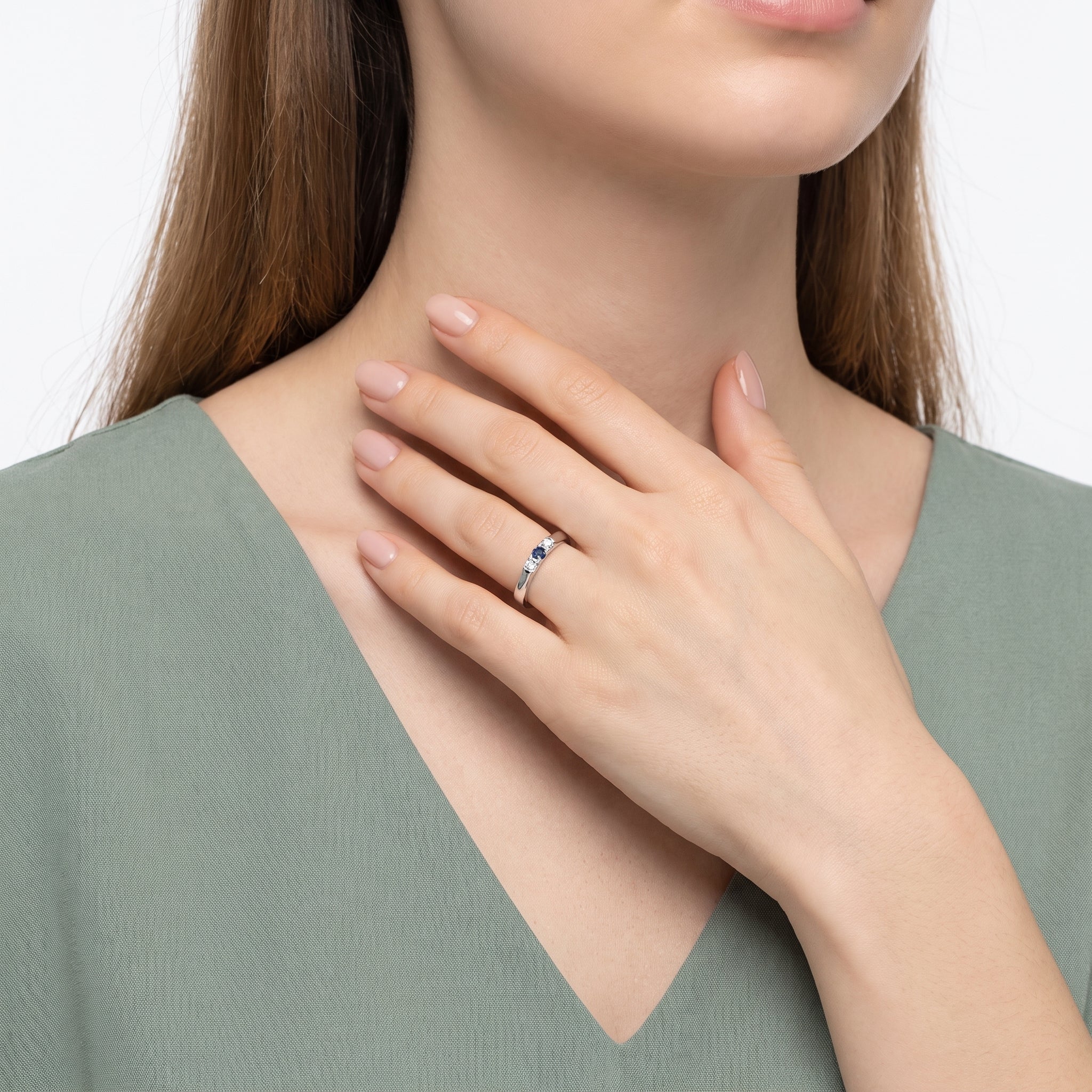 Hand at the collarbone with a silver three stone ring