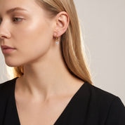 Gold round drop huggie turned toward the light, black dress
