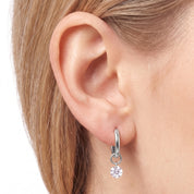 Silver huggie earrings with a small floating round crystal on the ear