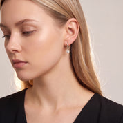Silver round drop huggie in a downcast beauty portrait