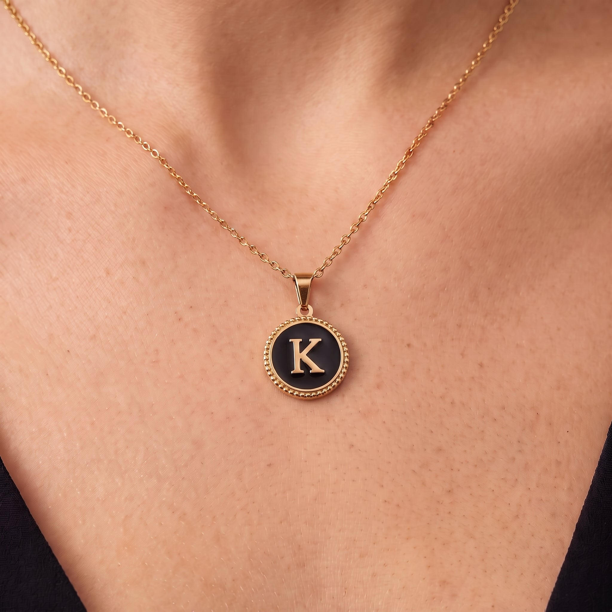Gold initial necklace with a beaded black letter K pendant on skin