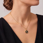 Perrine black beaded initial necklace worn with a black V-neck dress