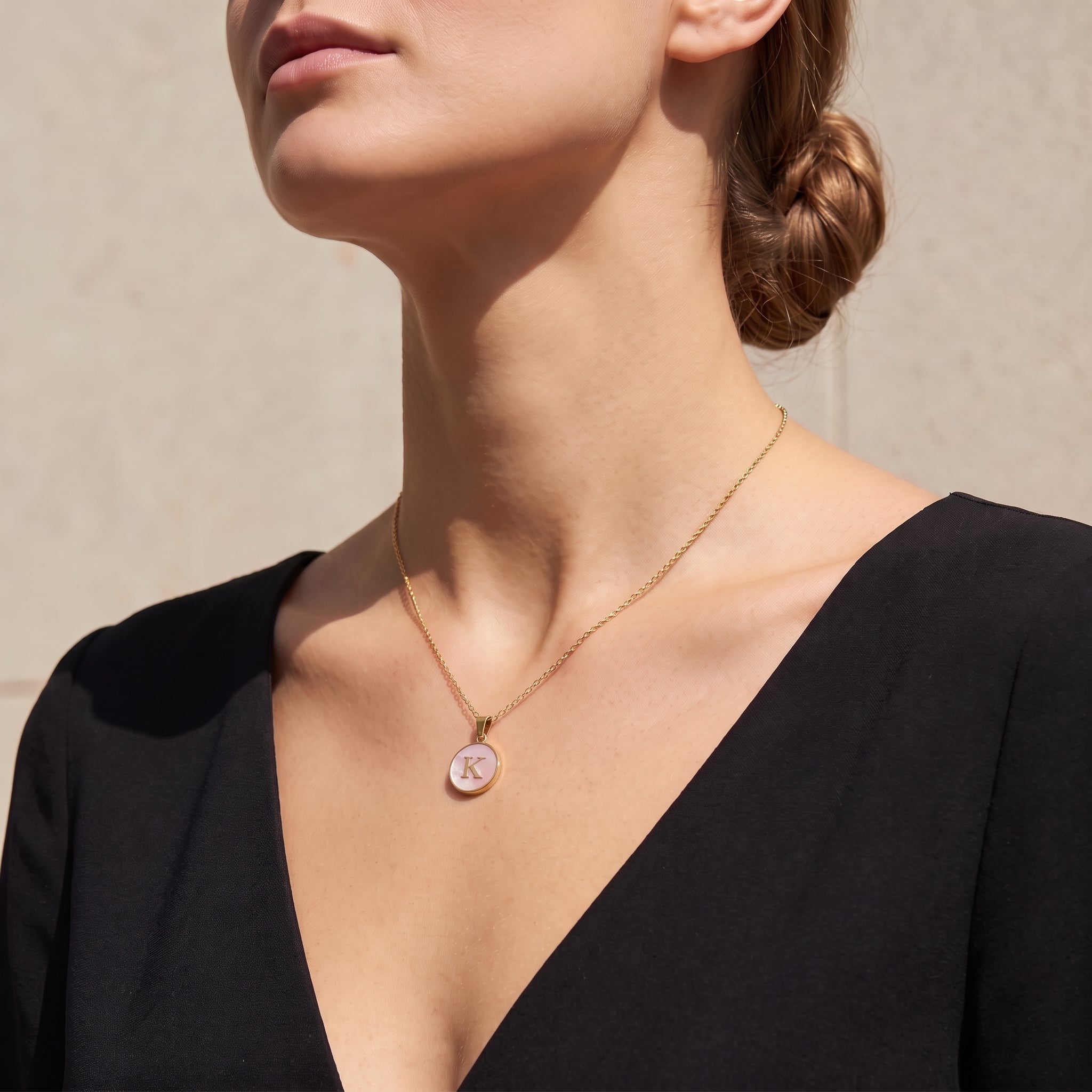 Perrine pink initial disc necklace at the collarbone in soft sunlight