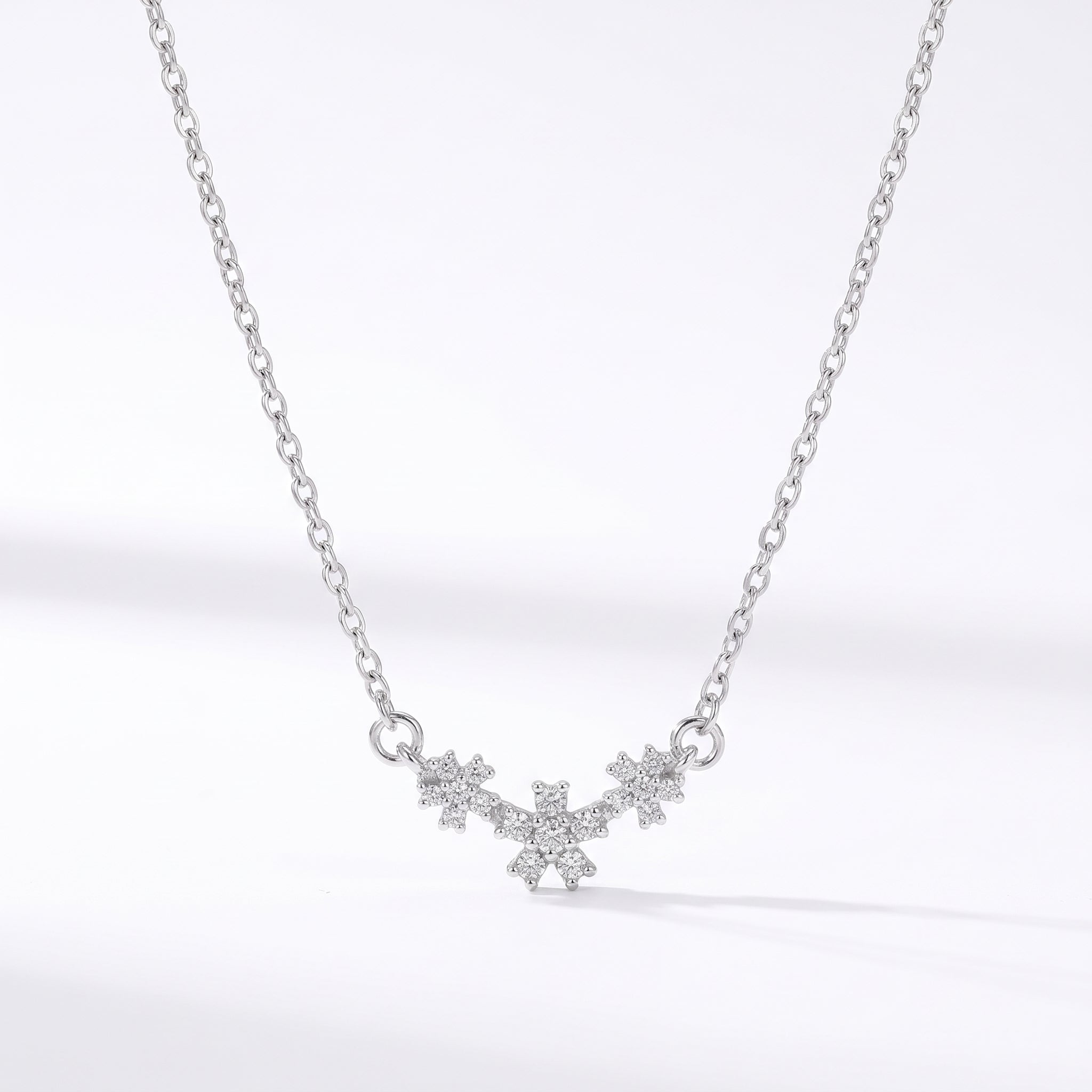 Silver necklace with three crystal daisies on a white background