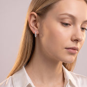 Silver rope huggie earring worn with the head tilted down