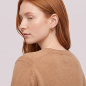Gold triple hoop earring seen over the shoulder, camel sweater
