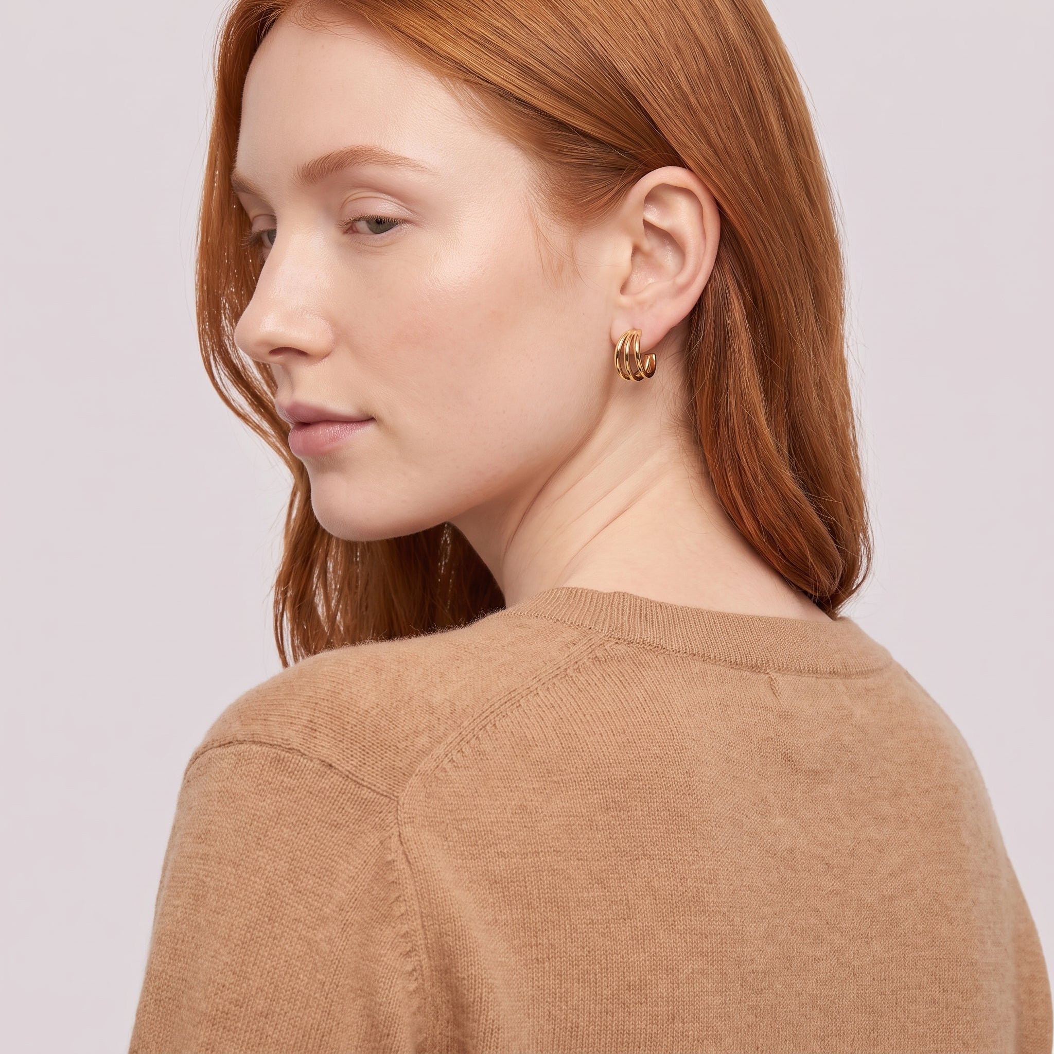Gold triple hoop earring seen over the shoulder, camel sweater