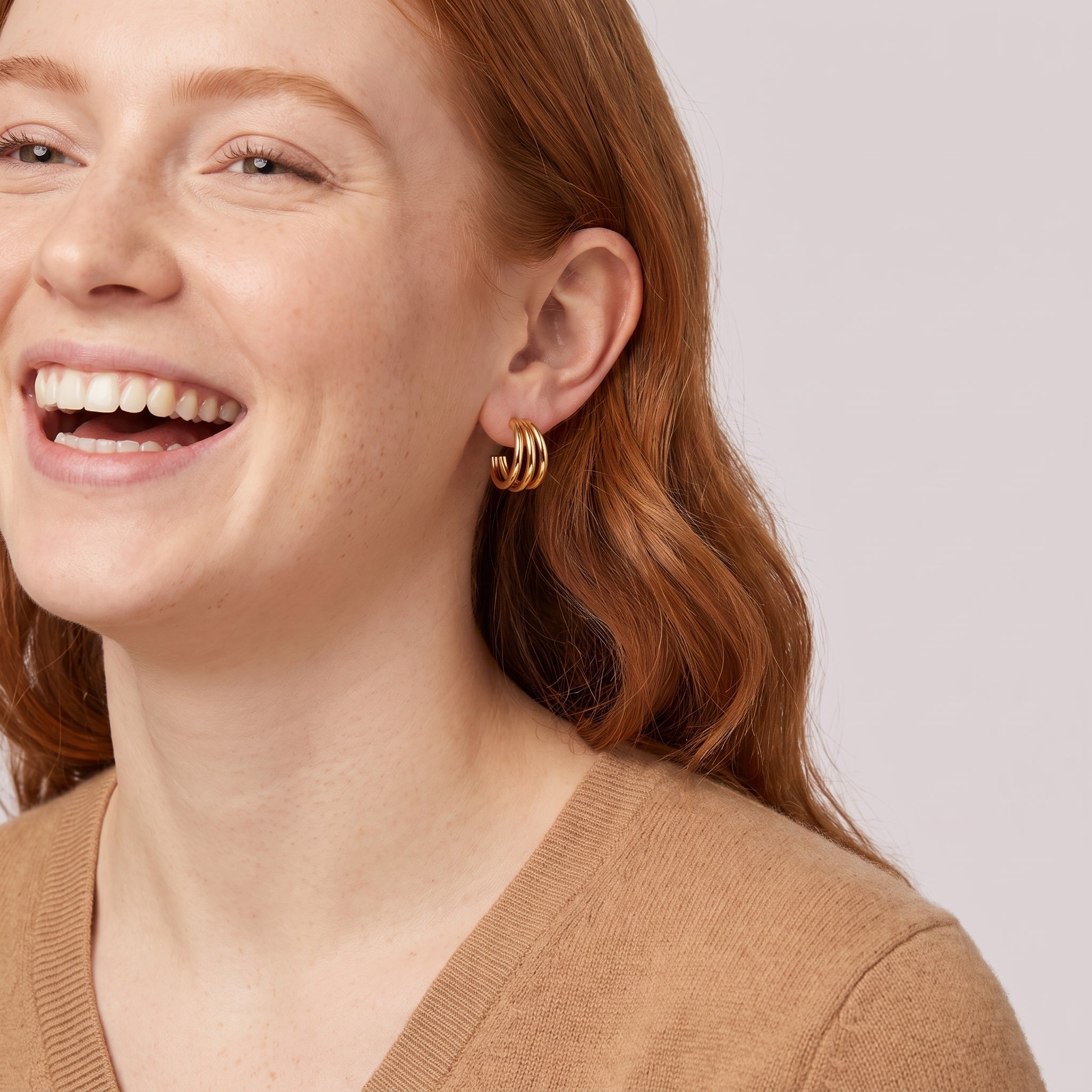 Gold triple hoop earring in a laughing portrait