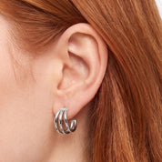 Silver triple hoop earrings hugging the earlobe in close-up