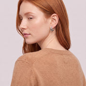 Silver triple hoop earring seen over the shoulder, camel sweater