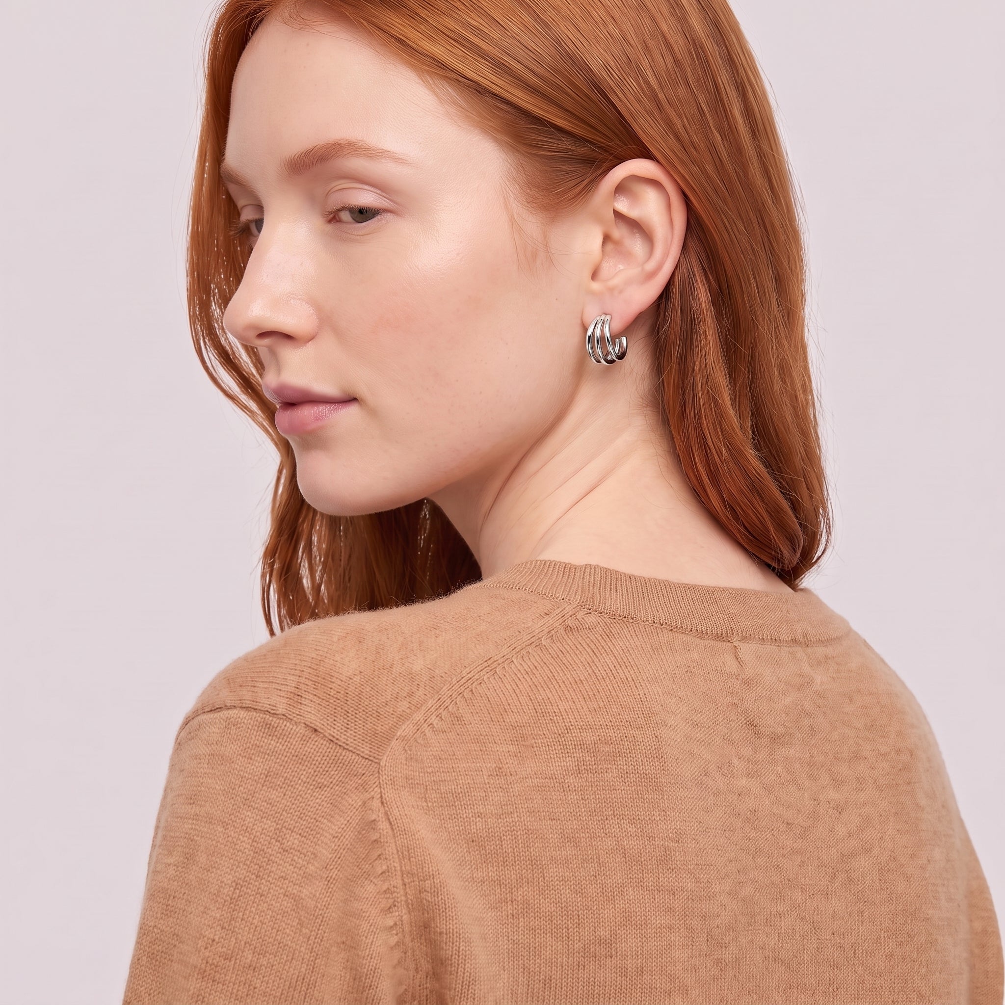 Silver triple hoop earring seen over the shoulder, camel sweater