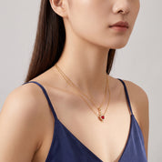Gold heart and sword necklace worn with a glance over the shoulder