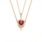 Gold heart and sword necklace laid out on a white background
