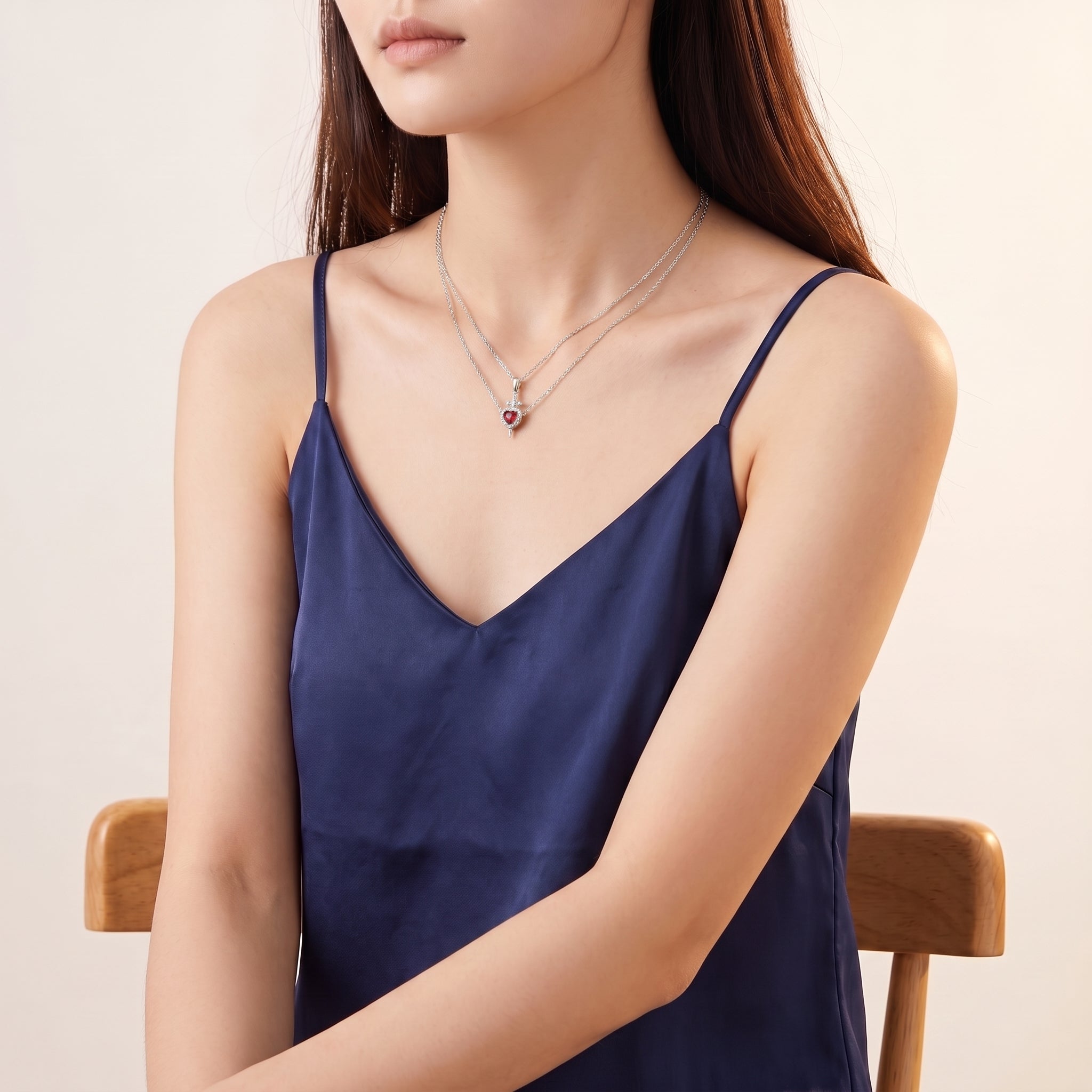 Silver heart and sword necklace worn in a seated portrait