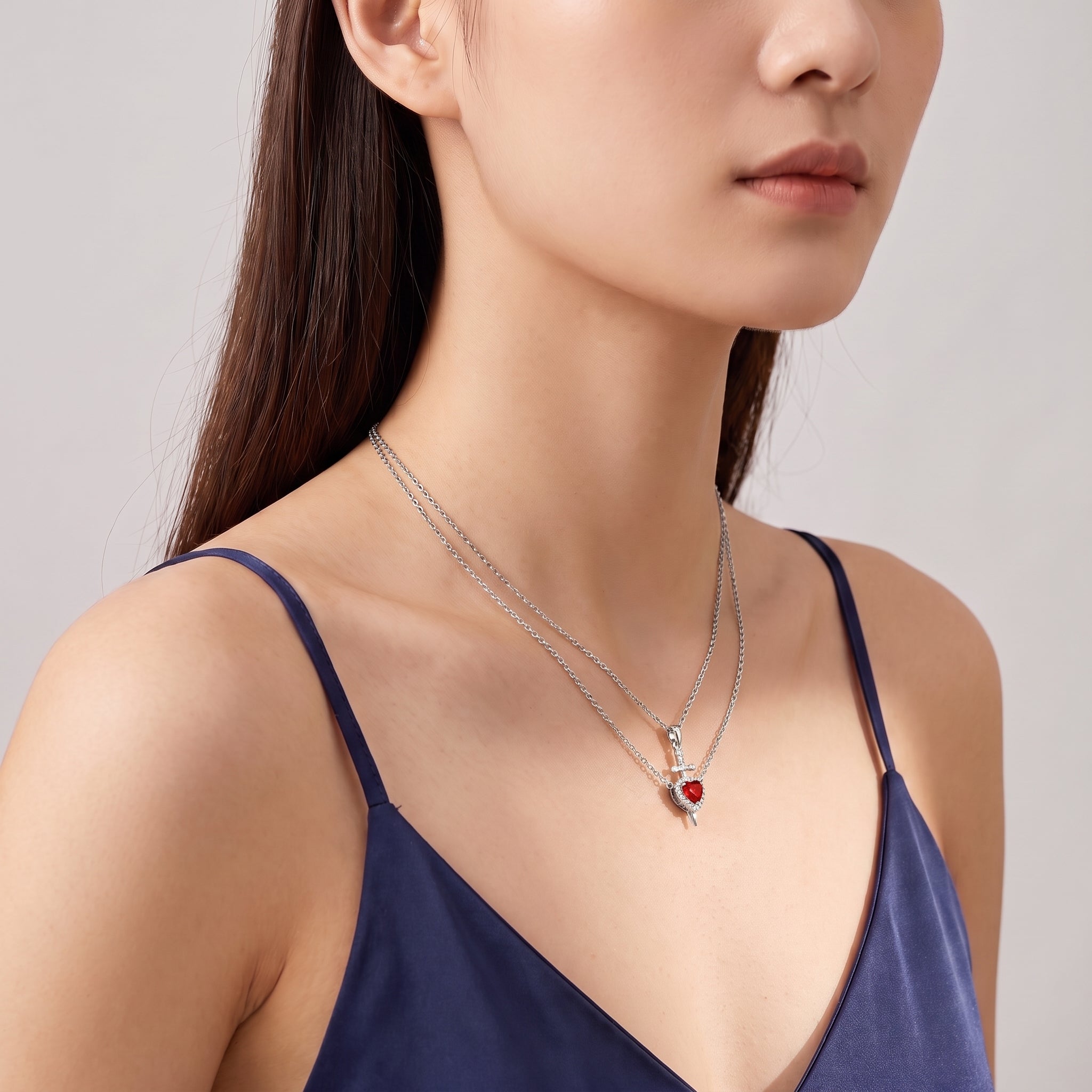 Silver heart and sword necklace worn with a glance over the shoulder
