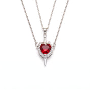 Silver heart and sword necklace laid out on a white background