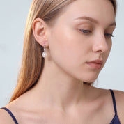 Downcast portrait of woman wearing silver Sabine round pearl drop earring