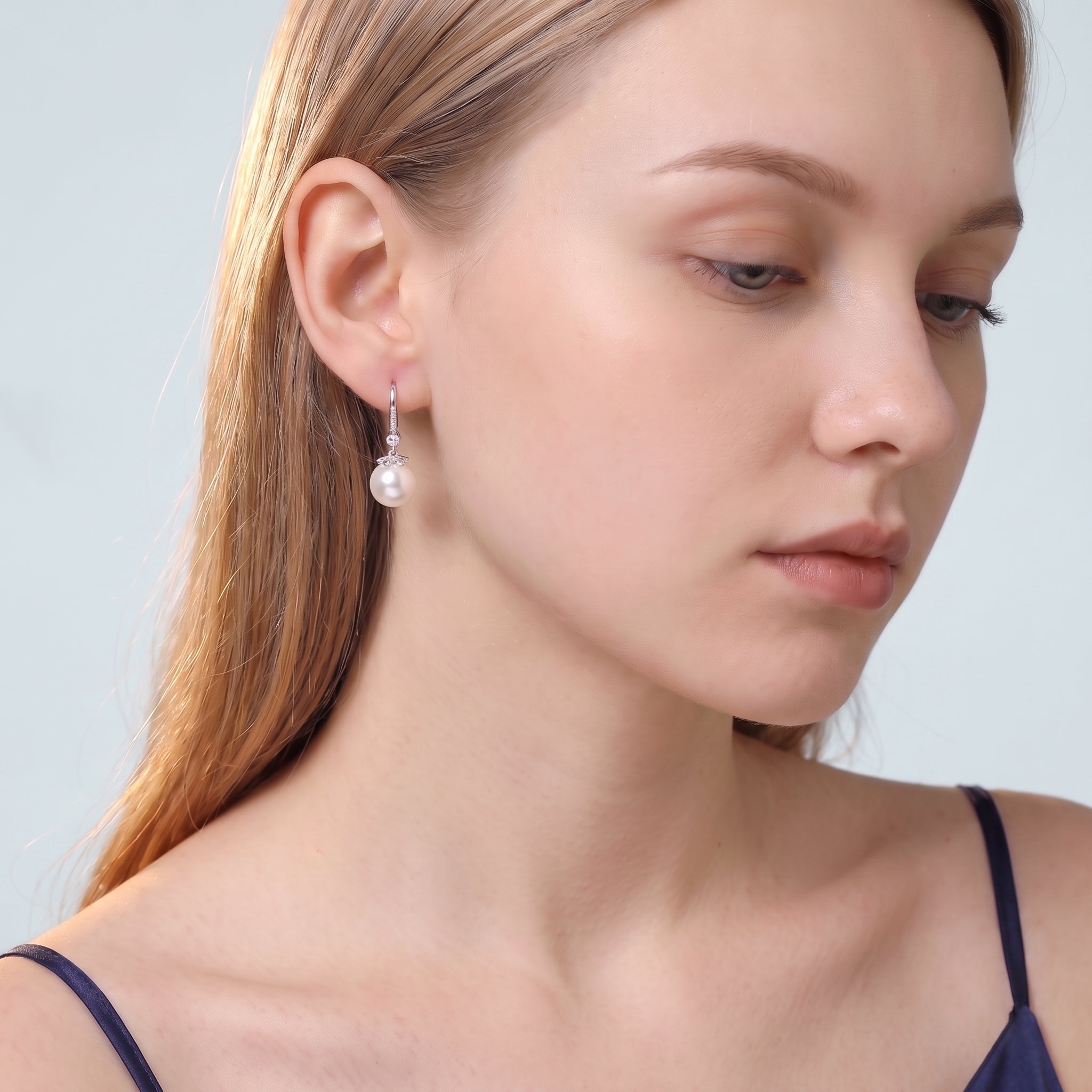 Downcast portrait of woman wearing silver Sabine round pearl drop earring