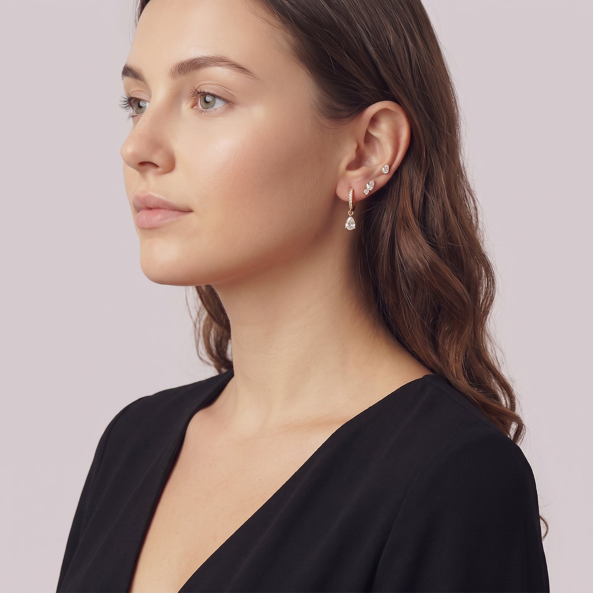 Gold earring set worn stacked, serene three-quarter portrait