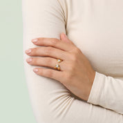 Gold pear open ring on a hand resting on the arm