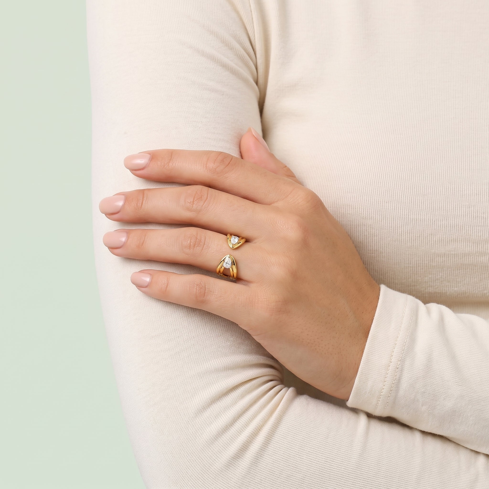 Gold pear open ring on a hand resting on the arm