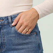 Gold pear open ring on a hand in a jeans pocket