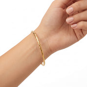 Gold twisted wire bangle worn loose at the wrist