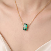 Close-up of the gold birthstone necklace's green crystal on the skin