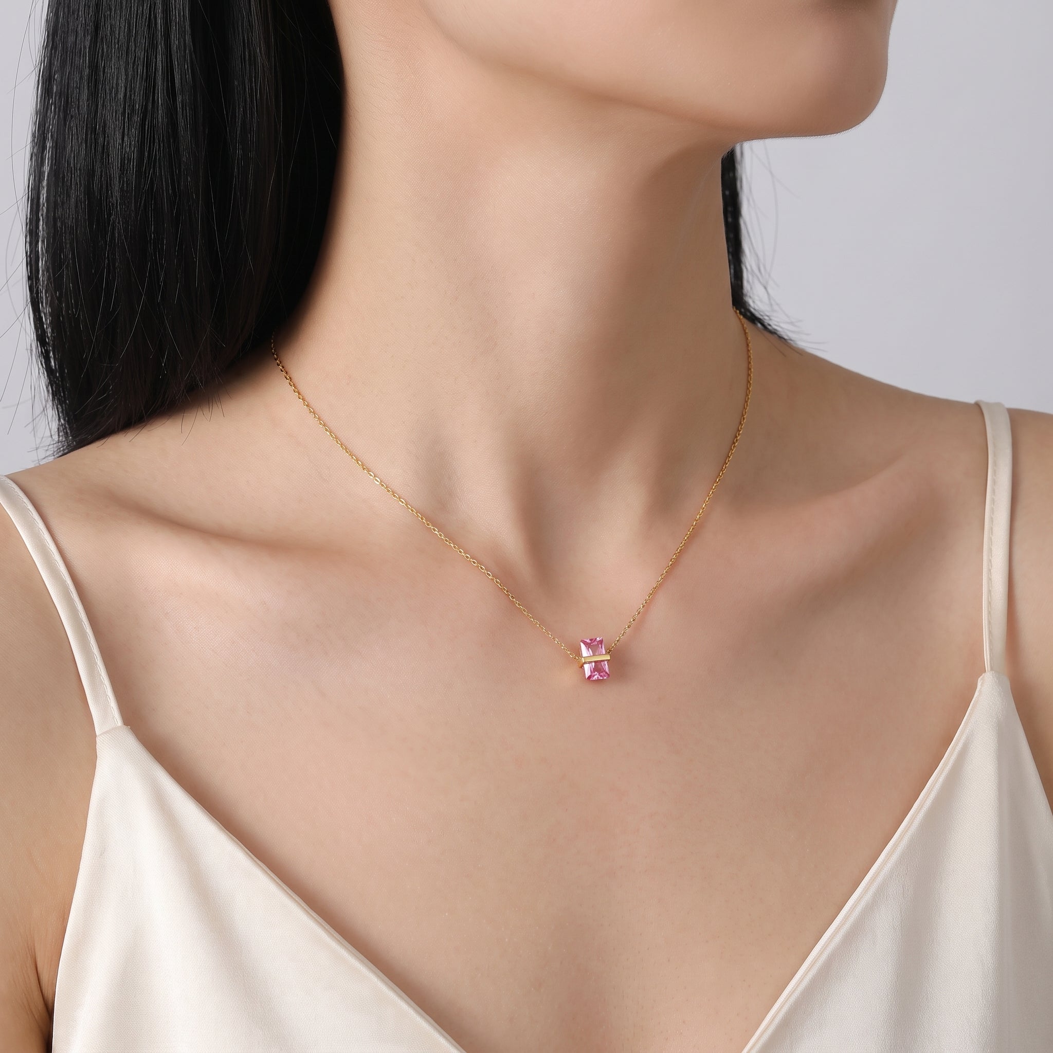 Gold birthstone necklace with a pink crystal worn at the collarbone