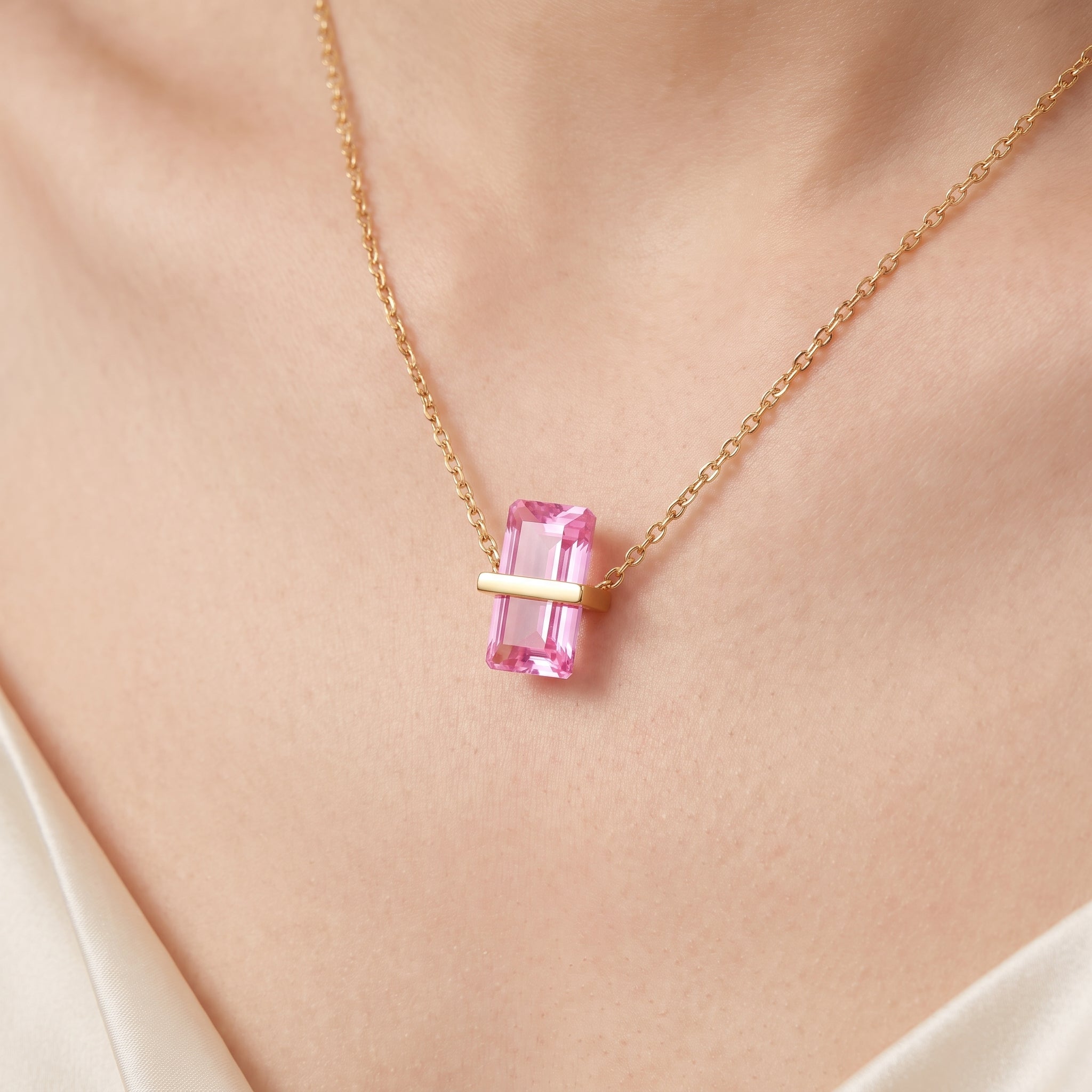 Close-up of the gold birthstone necklace's pink crystal on the skin