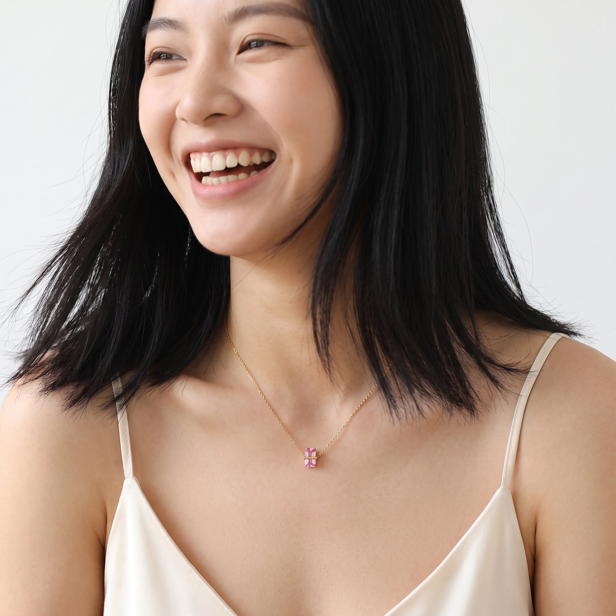 Gold birthstone necklace with a pink crystal worn in a candid portrait