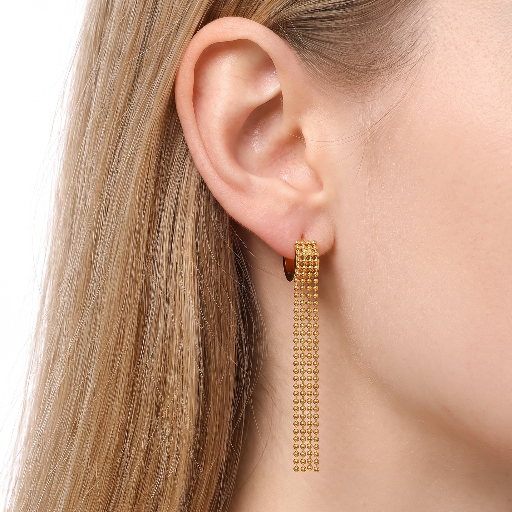 Gold ball chain tassel earrings worn on the earlobe