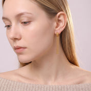Gold tassel earring in a downcast side portrait