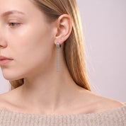 Silver tassel earring worn with an off-the-shoulder knit sweater