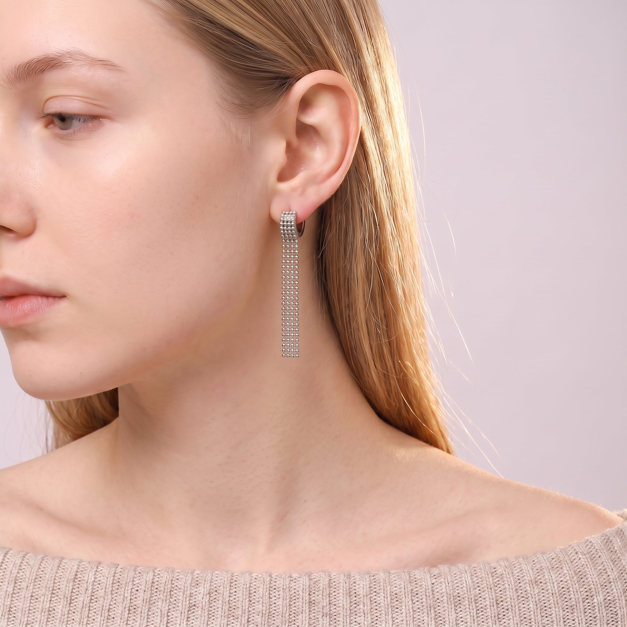 Silver tassel earring worn with an off-the-shoulder knit sweater