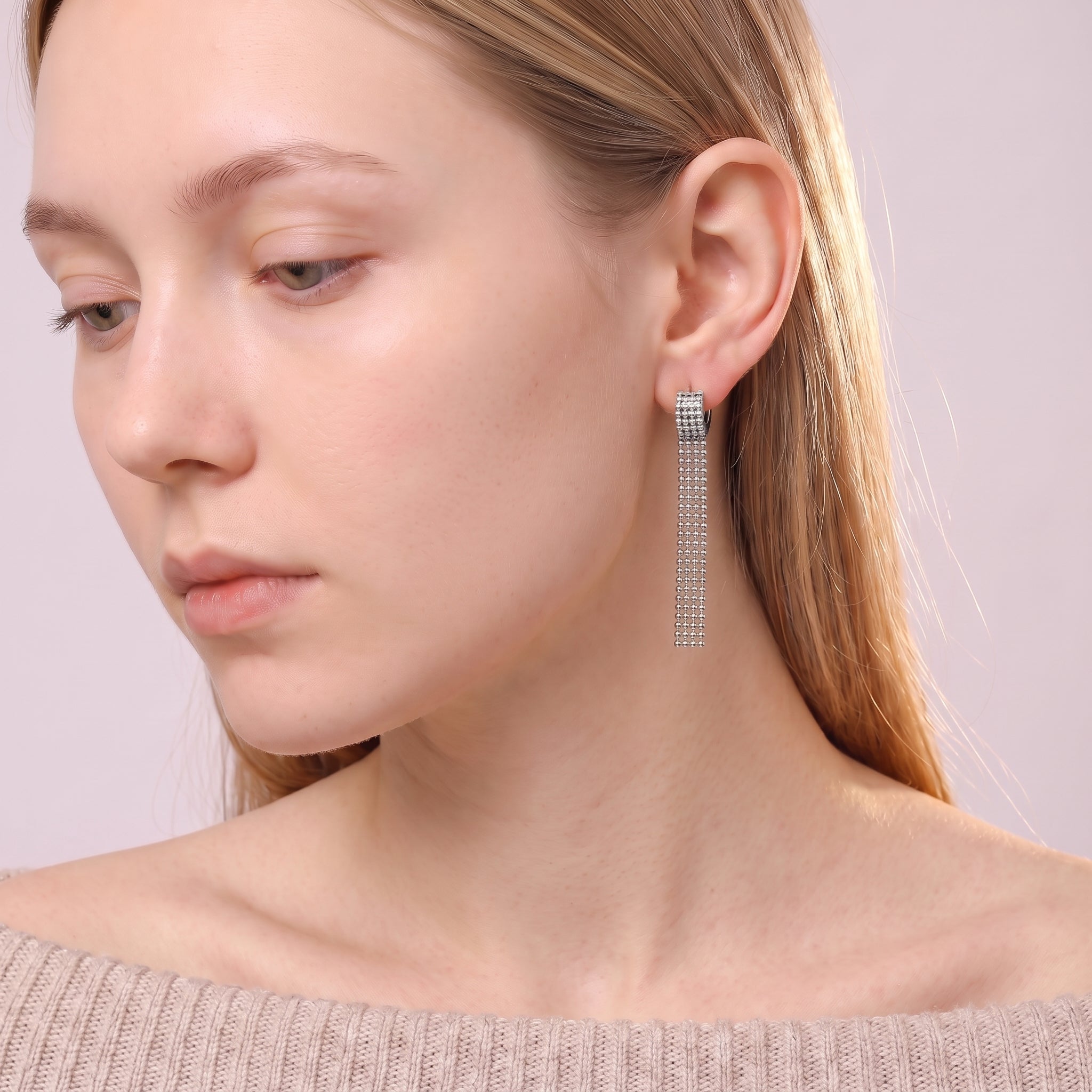 Silver tassel earring in a downcast side portrait
