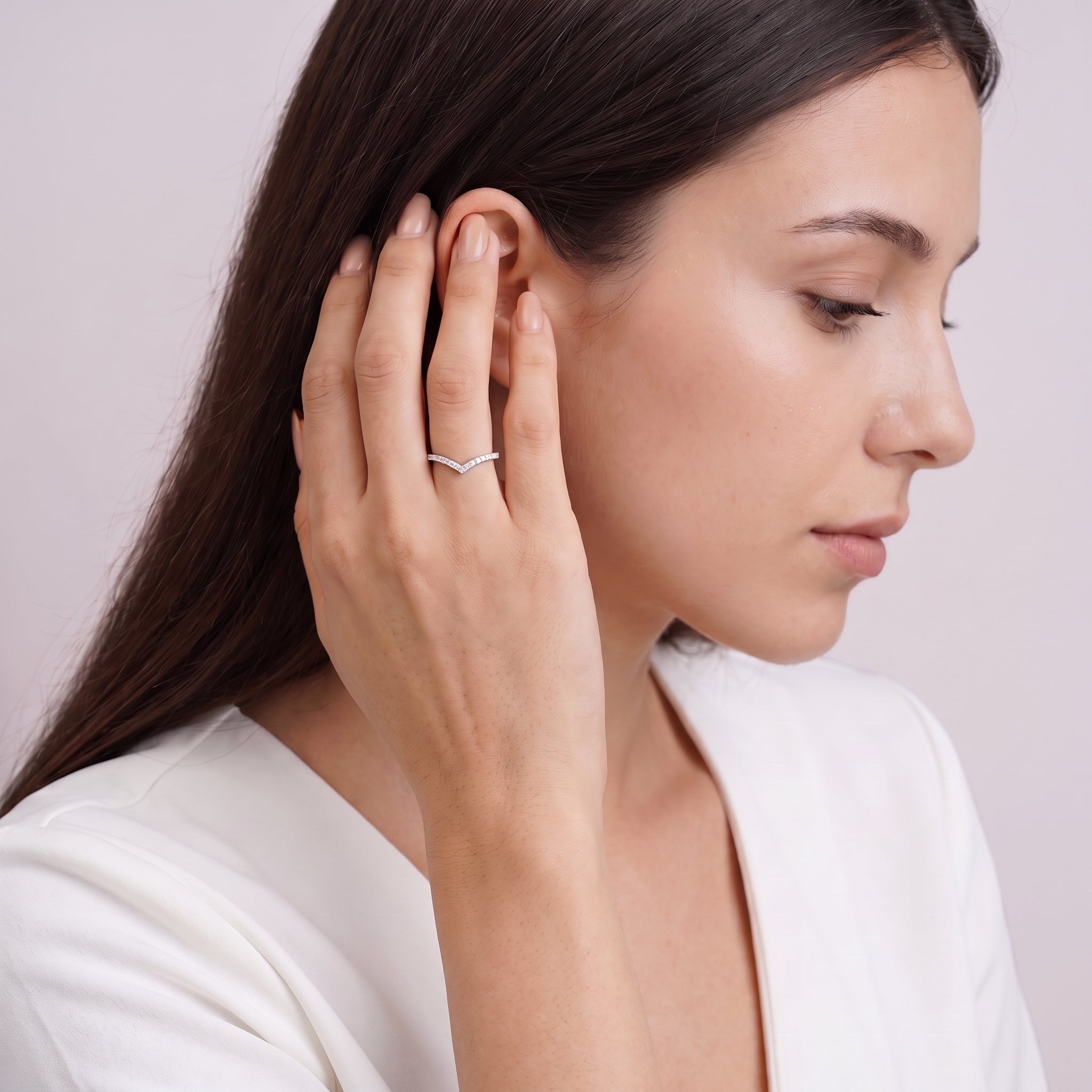 Woman tucking hair behind her ear wearing Soline silver chevron ring on pale mauve