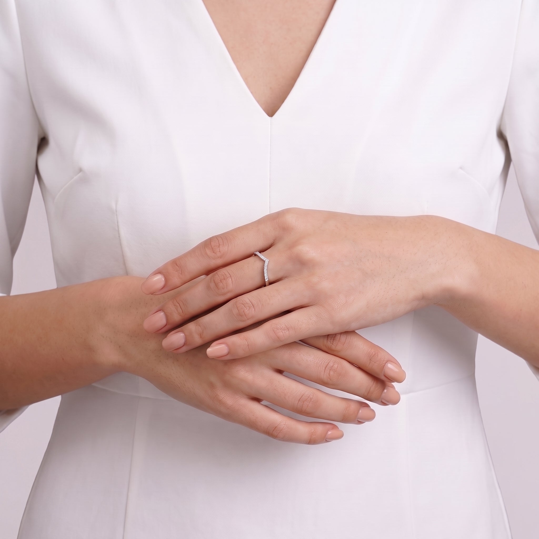 Hands clasped at the waist showing Soline crystal chevron ring with white top