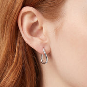 Silver twisted teardrop hoop earring worn on the earlobe, close-up