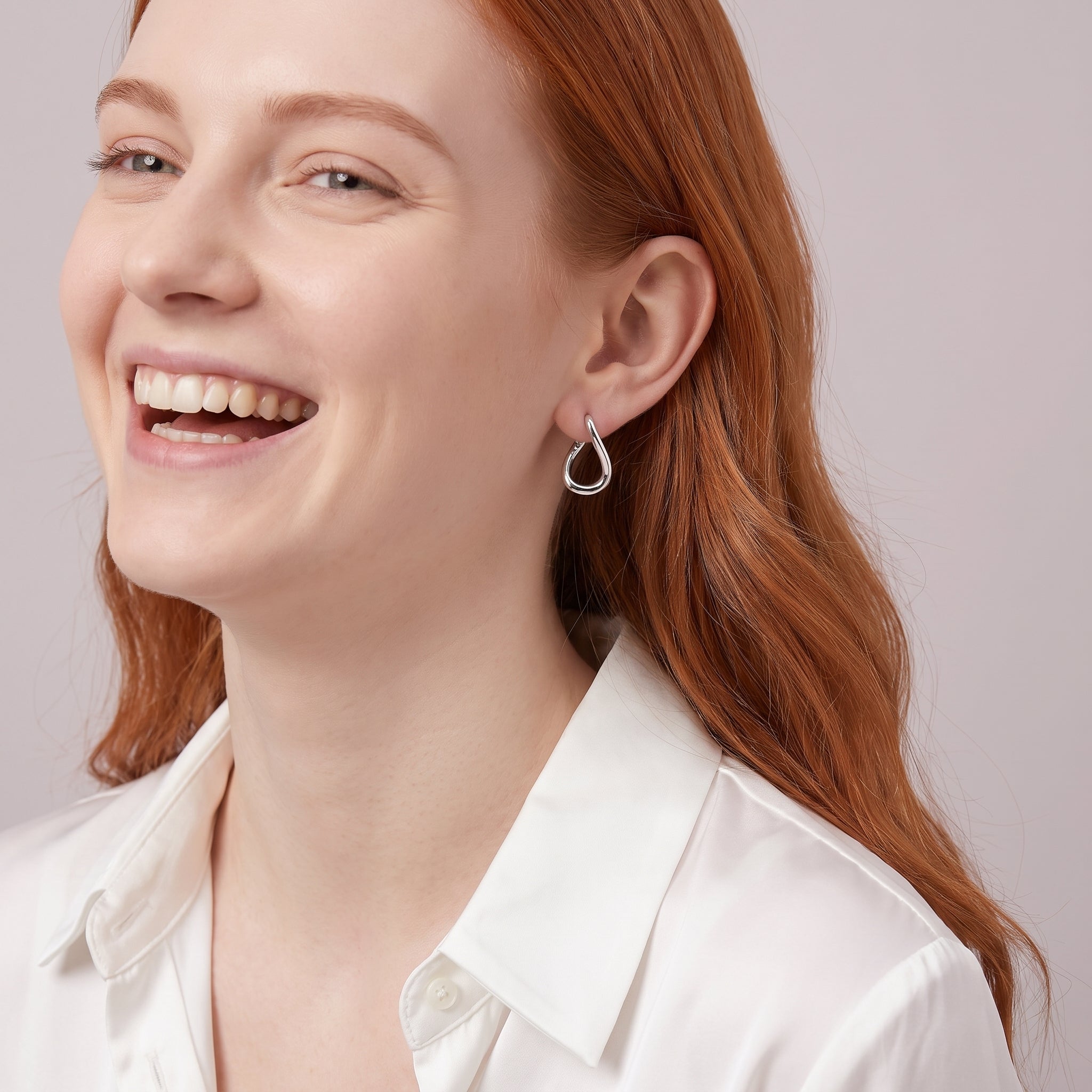 Silver twisted hoop earring worn with a white silk shirt