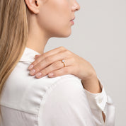 Hand on the shoulder wearing a thin gold solitaire ring